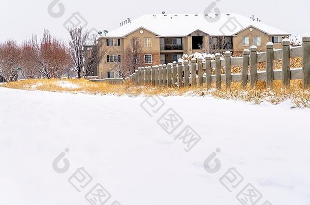 冬天，道路上覆盖着一层新鲜的白雪，背景是房屋