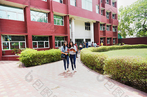 两位年轻女大学生朋友在校外大楼一起读书