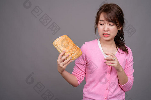 年轻的美丽的亚洲女人持有一块面包