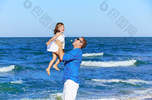 一家人的父亲抱着女儿在海滩上玩耍