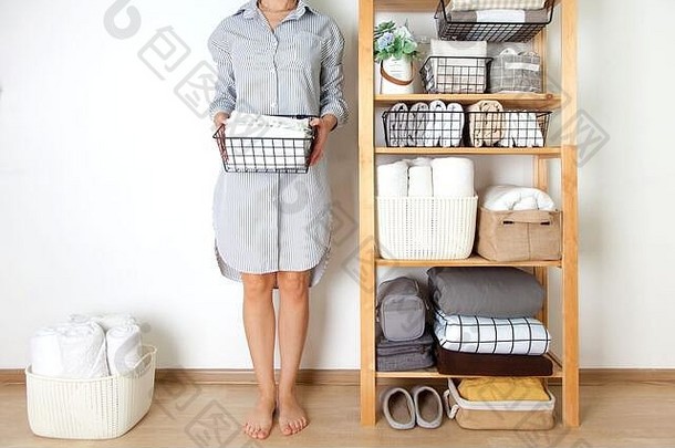 床单、羽绒被和毛巾垂直折叠。金属和织物黑色篮子。家务和储藏的概念。