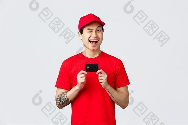 友好的微笑阿西安德elivery男人。红色的帽t恤统一的眨眼快乐的推荐信贷卡买非接触式病毒爆发