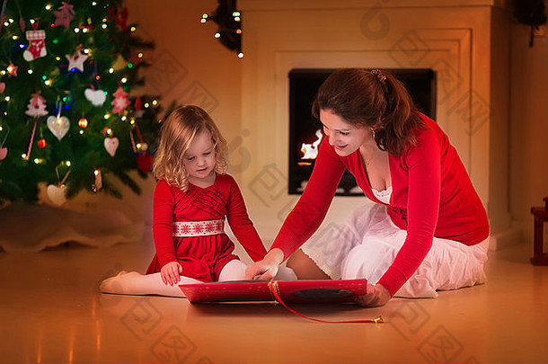 妈妈。女儿读书壁炉圣诞节夏娃家庭孩子庆祝圣诞节装饰房间树