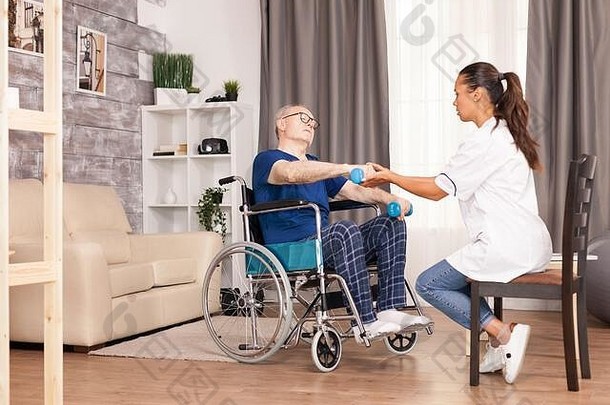 坐在轮椅上用哑铃训练手臂疼痛的老年人。残障老人康复支持治疗物理治疗<strong>保健</strong>系统<strong>养老</strong>院社工