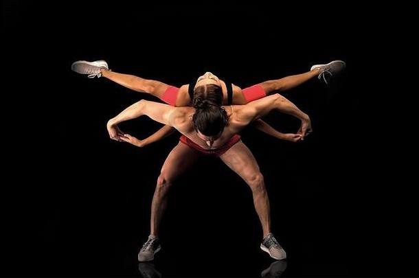 运动瑜伽情侣。一起跳舞。它们相辅相成。在健身房进行双人训练。健康的生活方式。显示出良好的体形。与健身有关。男人和女人在黑色的舞台上跳舞。