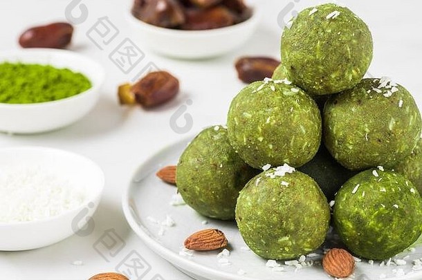 自制的生能源球使绿色火柴茶日期坚果健康的素食主义者甜点食物白色背景关闭