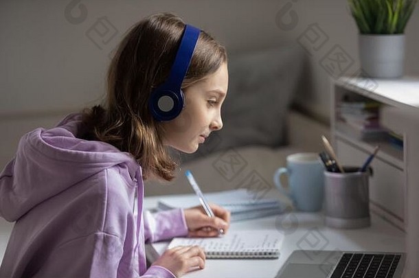戴耳机的少女在家里用笔记本电脑学习