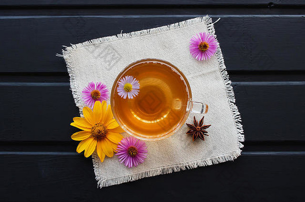 花茶放在一个透明的玻璃杯里，放在黑桌子上。治疗茶。