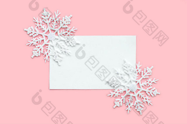 粉红色背景上饰有雪花的白纸卡片。新年、圣诞节和冬季概念。平面布局、俯视图、可用空间。