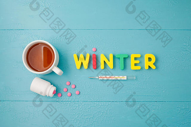蓝色背景上有温度计、药片、皱巴巴的餐巾、铭文“冬天”和茶