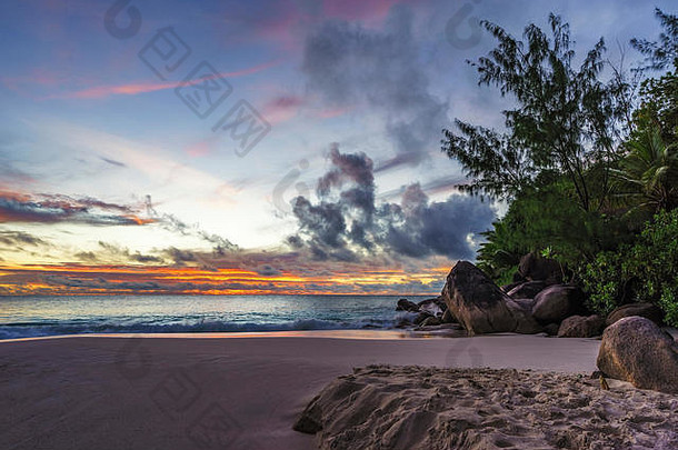 美丽浪漫的紫色和橙色日落在天堂海滩上，花岗岩岩石、棕榈树、沙滩和安斯·乔其特（anse georgette）、普拉斯林（praslin）的海洋，