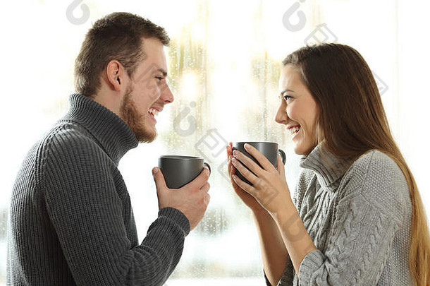 一对相爱的幸福夫妇在家里的冬天雨天相望的侧视图