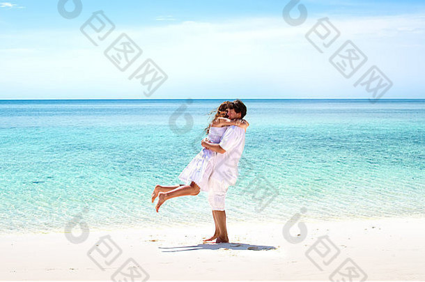 美丽的年轻夫妇在美丽的热带海滩拥抱