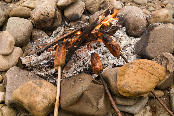 河边卵石<strong>海滩</strong>上的篝火上煮香肠
