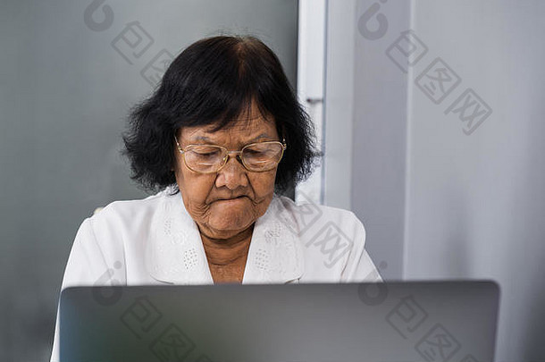 在笔记本电脑上工作的压力很大的老妇人