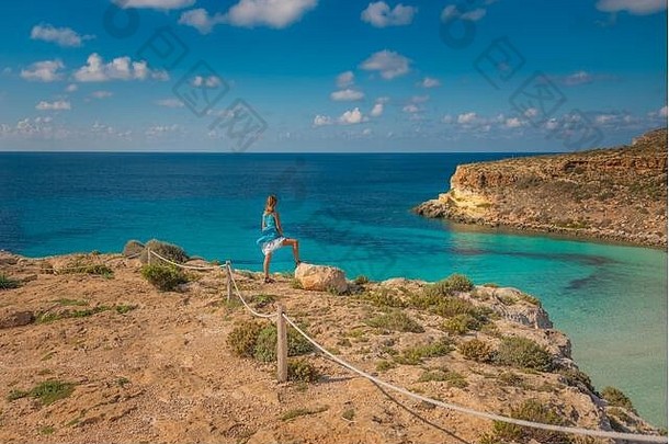 兰佩杜萨岛（Lampedusa）是西西里岛南部远洋群岛的一个天堂岛，一位年轻的金发女郎正<strong>在</strong>欣赏令人惊叹的兔子海滩美景