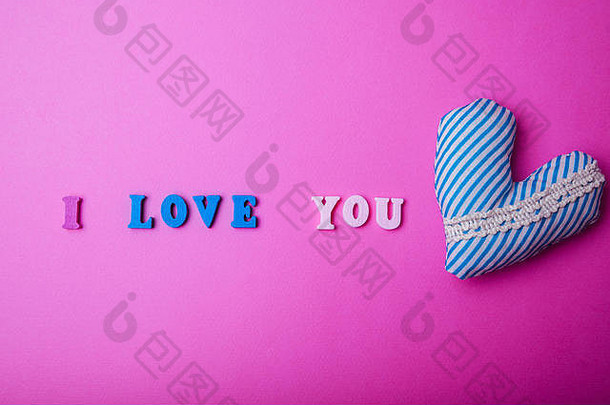 在<strong>粉色</strong>纸背景上写着“我爱你”的心。情人节的概念。