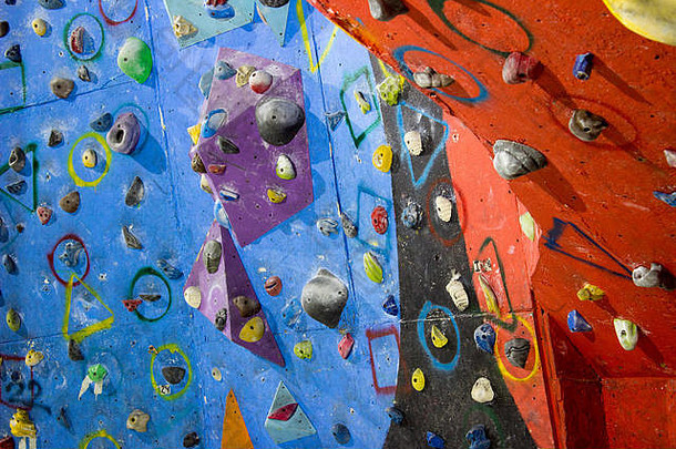 攀岩馆的攀岩墙，有不同颜色和形状的岩石和把手。