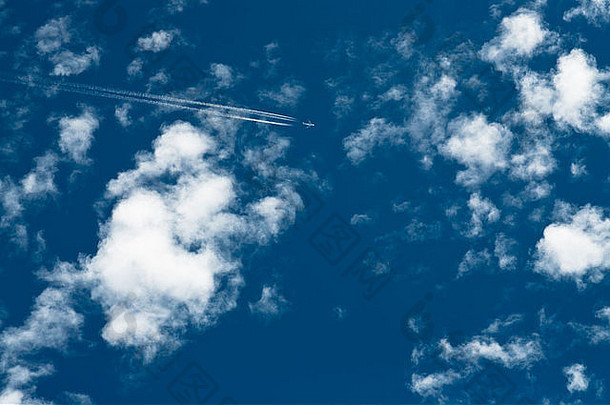 喷气式飞机在蓝色的天空中飞行，伴随着白色的积云。