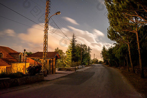 这是一个长时间曝光拍摄的镜头，你可以在月光下看到一条路，附近的房子发出橙色的光