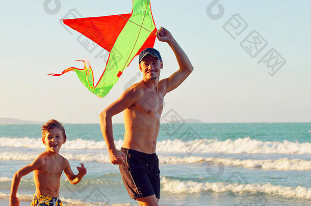 父亲带着儿子，日落在海边放风筝，幸福的家庭