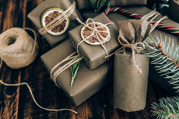 礼品和礼品用牛皮纸包装，棕色木质背景上有装饰。假日零浪费概念。