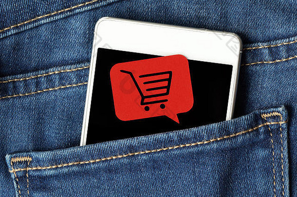 牛仔裤口袋里的智能<strong>手机</strong>和购物车上的信息泡泡-在线购物概念