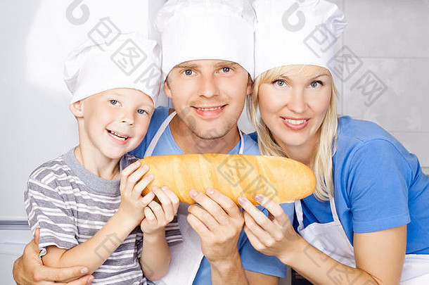 幸福家庭：爸爸、妈妈和儿子在家里的厨房里做饭，手里拿着面包