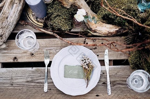 婚礼餐桌招待会。在冰岛的灰色草地上，一张供两个建筑托盘使用的临时桌子。<strong>浅紫</strong>色盘子、障碍物、苔藓