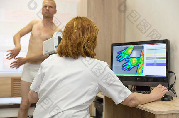 一个年轻人在医生招待会上进行热像研究，用热像仪检查他的手的四肢
