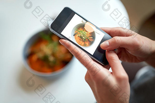 在咖啡馆用智能手机拍摄食物的女人