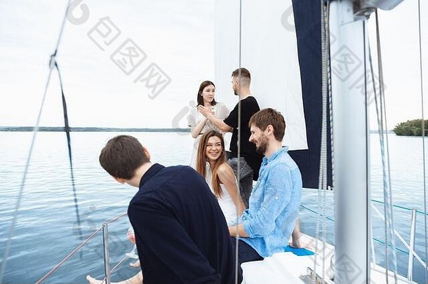 一群快乐的朋友在户外的船上聚会上喝着<strong>伏</strong>特加鸡尾酒，兴高采烈。年轻人享受海游、青春和<strong>暑</strong>假的乐趣。喝酒、度假、休息。