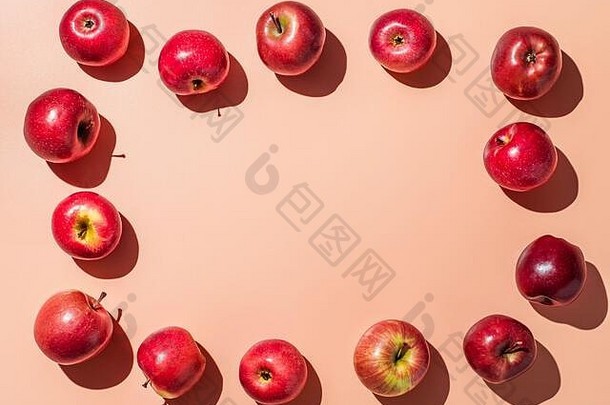 橙色或珊瑚粉色背景上的红苹果，中间有文本或设计的空间，彩色水果架。创意概念。平放或俯视图，强光