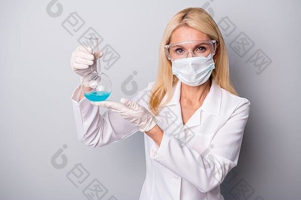 成功退休的退休女科学家持有化学液体瓶进行冠状病毒解毒试验戴橡胶手套呼吸面罩护目镜