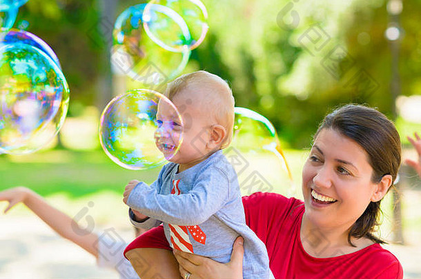 可爱的宝宝和他的妈妈在夏天抓肥皂泡