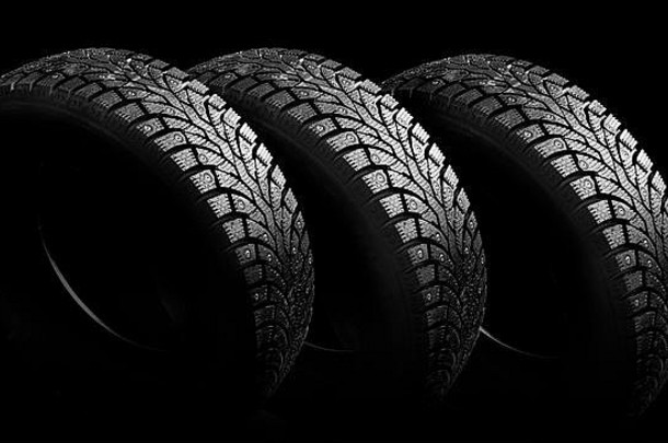 黑色背景特写上带尖刺的冬季橡胶。保证冬季安全。带轮胎的机架背景上的冬季轮胎。