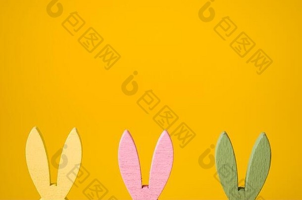 复活节兔子黄色、粉色、绿色耳朵，背景为黄色