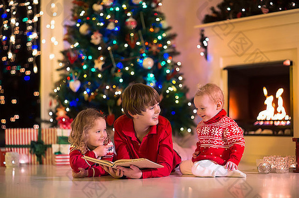平安夜，孩子们在壁炉边看书，打开礼物。一家人带着孩子庆祝圣诞节。用树装饰的房间
