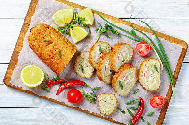 特写镜头：的鱼糜面包，里面装满了洋葱、鸡蛋、胡萝卜，切成片，配上青葱、欧芹、西红柿和土豆片