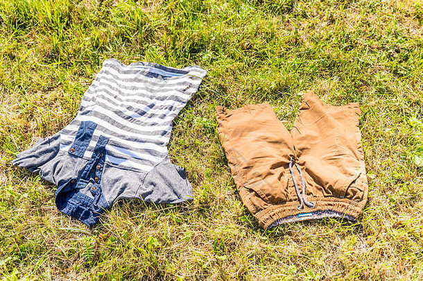 阳光明媚下，孩子们的衣服躺在草地上。