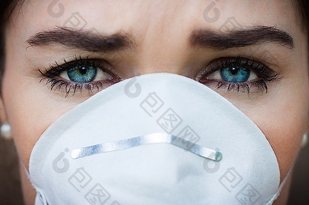 一位不幸的妇女戴着口罩病毒或污染的特写照片。