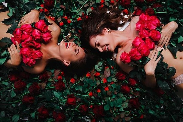 两个黑发女郎躺在花上，满身是红玫瑰