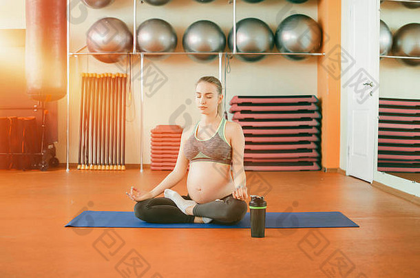 <strong>孕妇</strong>瑜伽。年轻漂亮的怀孕女孩坐在莲花座上做瑜伽和手摸泥