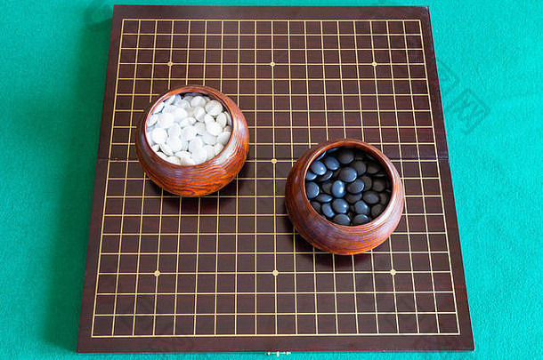 绿色桌子上木板上的白色和黑色玩围棋用石头的顶视图