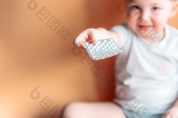 一个蹒跚学步的小孩手里拿着一个盘子，盘子里放着药片，药片没有聚焦