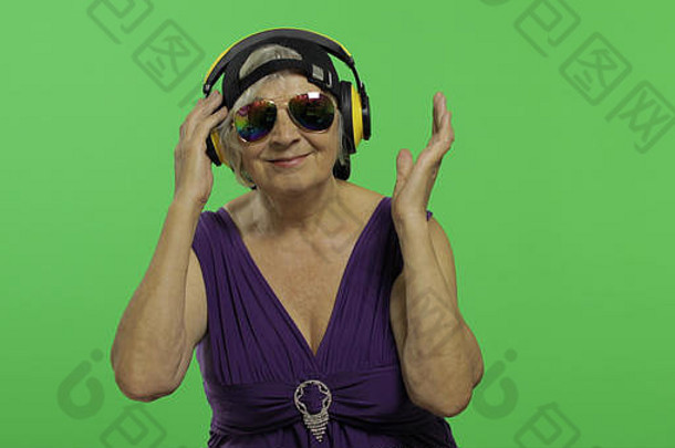 上了年纪的女人听音乐耳机舞蹈漂亮的快乐祖母太阳镜帽的地方标志文本浓度关键绿色屏幕<strong>背景</strong>