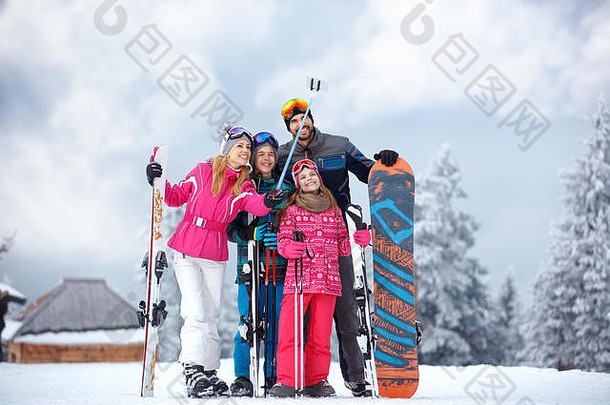 一家人在寒冷的日子里滑雪，在雪地上享受寒假，在山里进行移动自拍