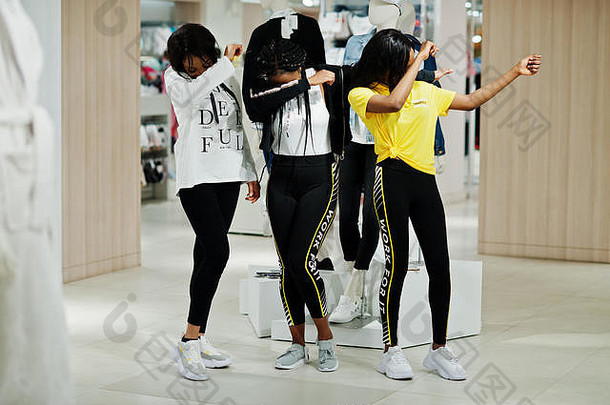 三名穿着运动服的美国黑人妇女在运动<strong>服装</strong>商场与人体模特比赛。运动商店主题。显示dab。