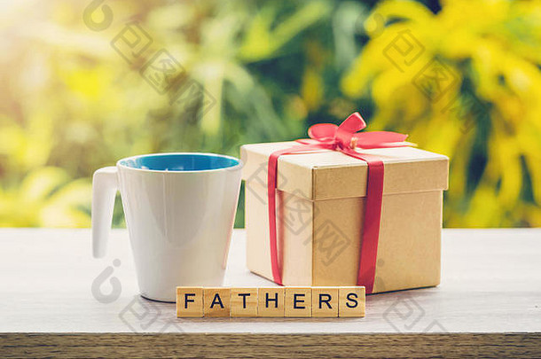 阳光普照的木桌上的快乐法特雷节概念咖啡杯和礼品盒。