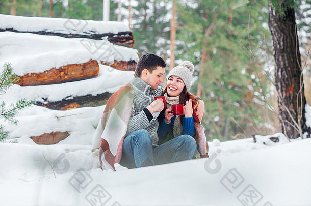 微笑年轻的夫妇杯坐着雪公园喝热饮料有趣的